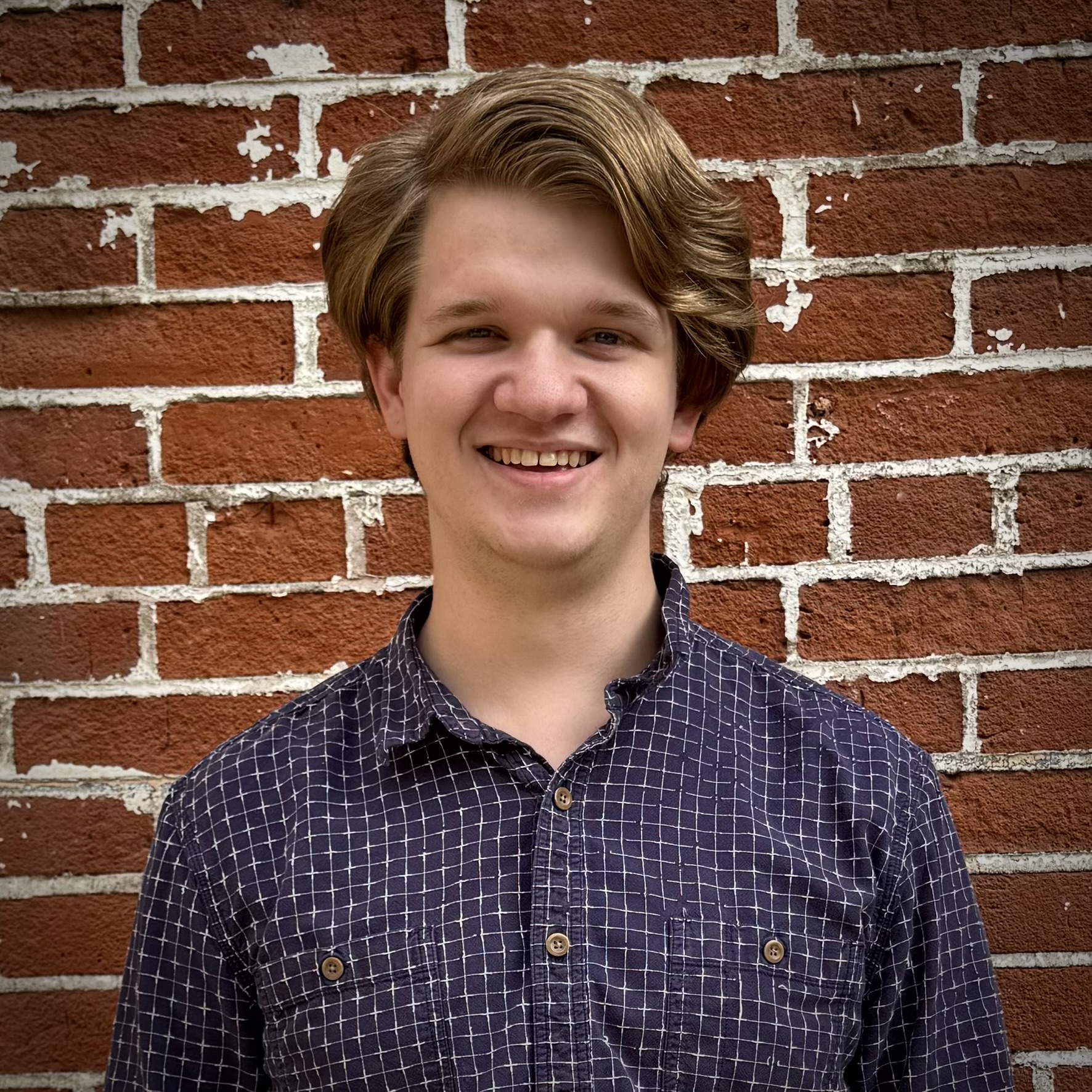 Matthew Mahoney smiling in front of a brick wall